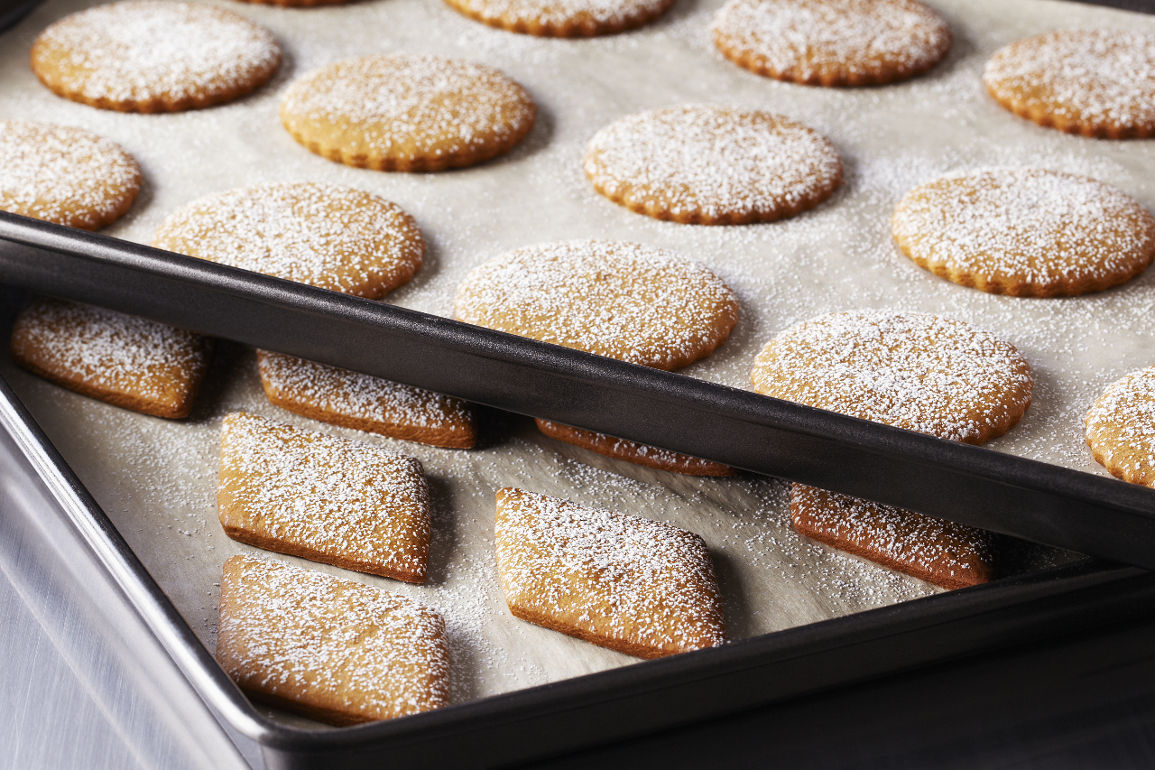 A shot of Anna Olson's basic gingerbread cut-out cookies sprinkled with icing sugar on a baking tray