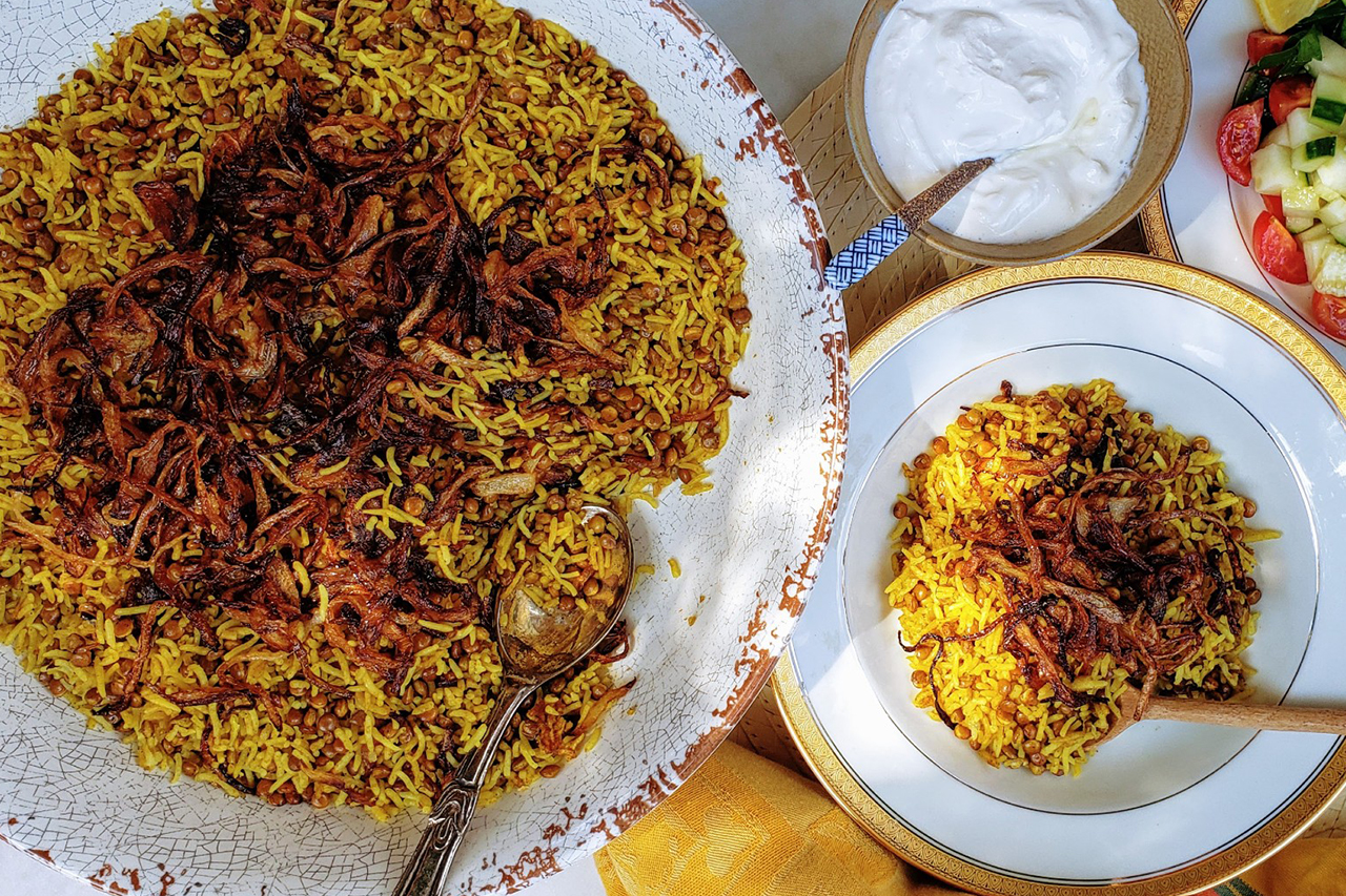 Plate of mujadara beside a larger bowl of the dish