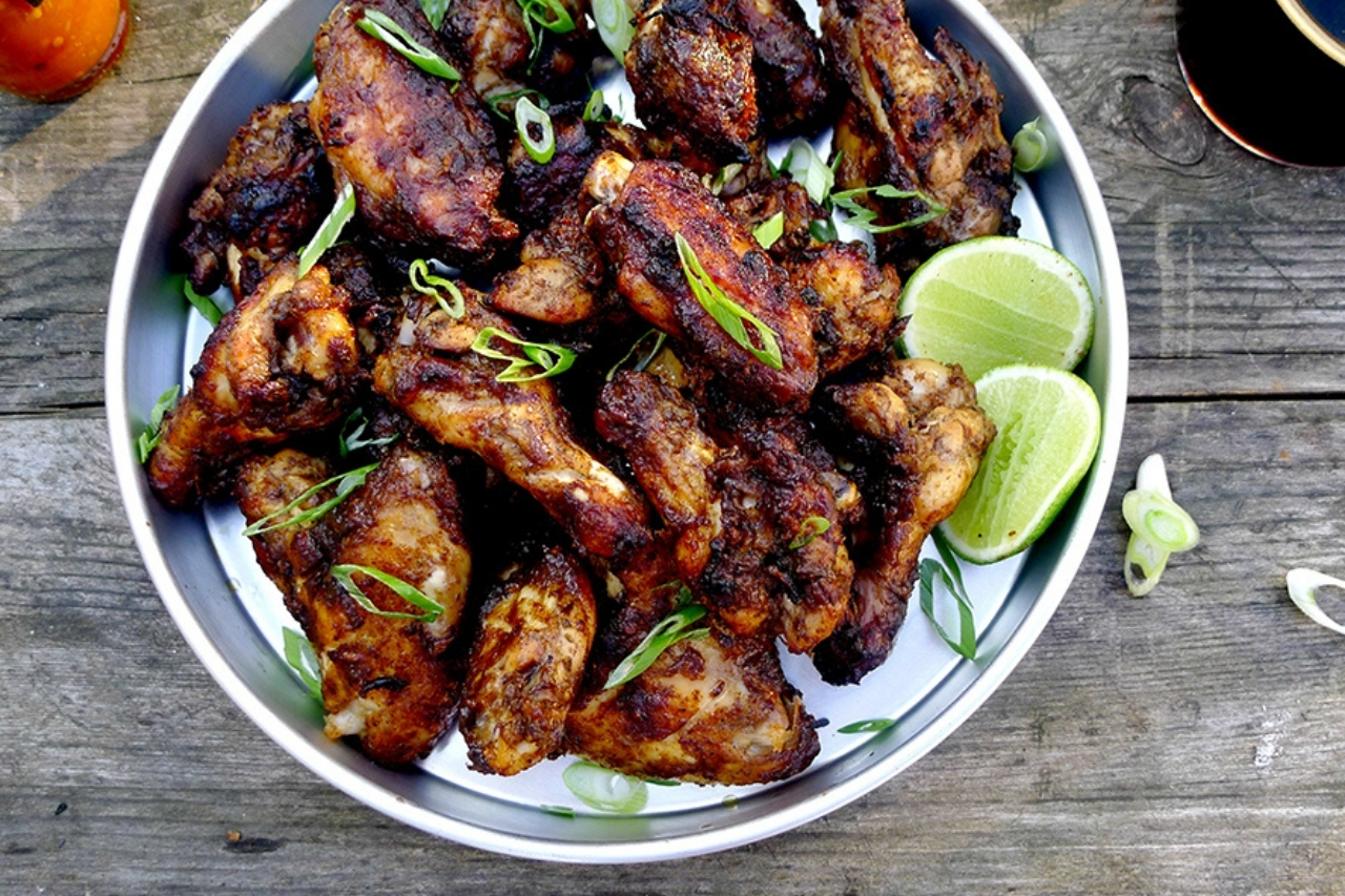 A plate of jerk chicken wings with lime