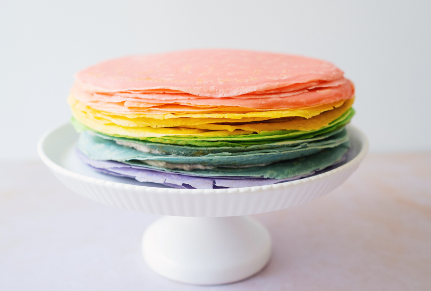 rainbow crepes stacked on a cake stand