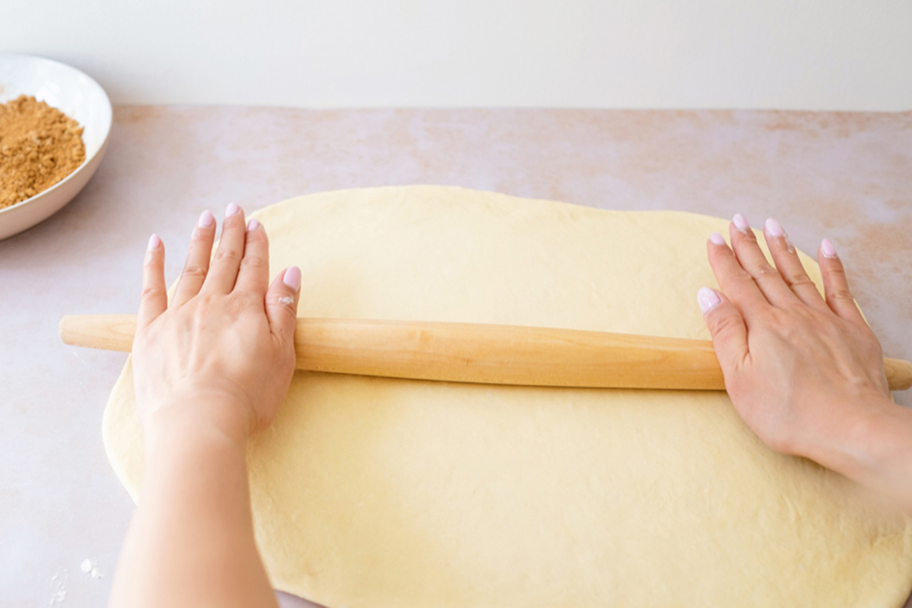 Cinnamon rolls dough being rolled