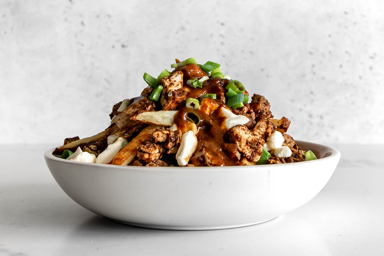 a bowl of curry chicken poutine