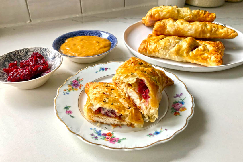 a turkey dinner hand pie on a patterned plate, cut in half to show filling