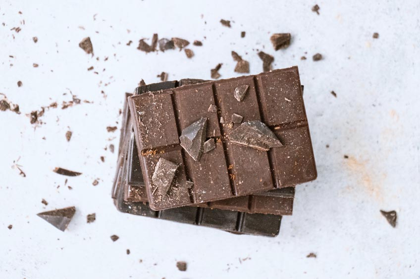 A stack of crumbly dark chocolate on a stone countertop