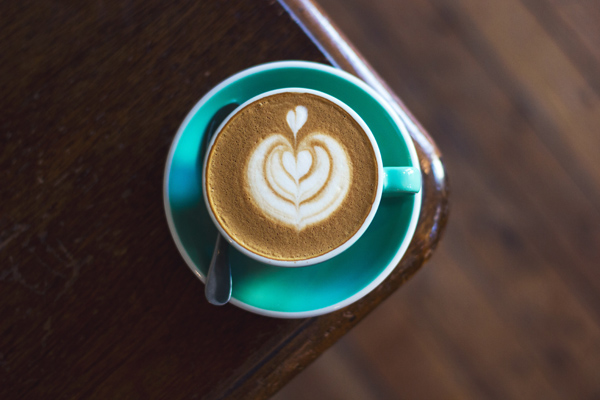 A frothy cappuccino in a teal cup on a cafe table