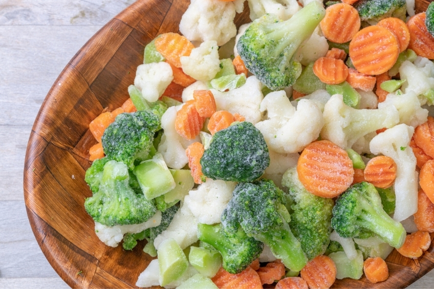 Frozen vegetables in a bowl including frozen carrots, broccoli and cauliflower