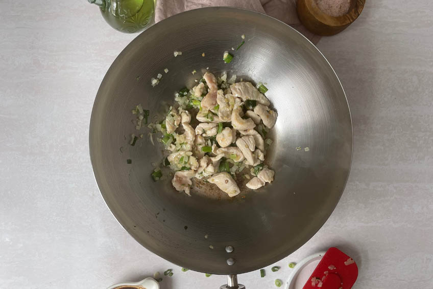 Chicken, ginger, onions and green onions cooking in a wok