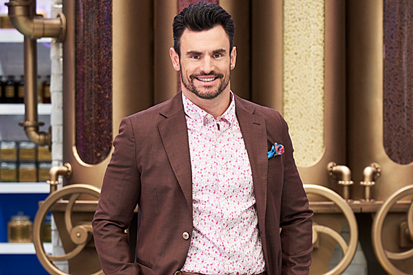 Steve Hodge smiles while wearing a brown suit and floral shirt