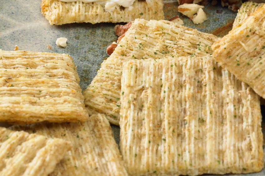 A closeup of a pile of Triscuit Crackers on a stone countertop