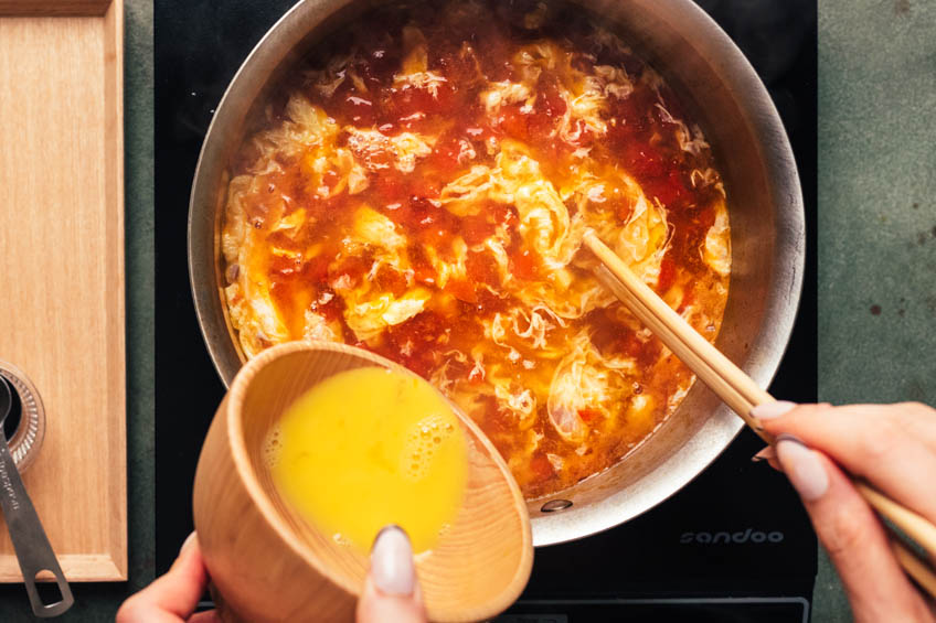 Eggs being whisked into Chinese tomato egg drop soup