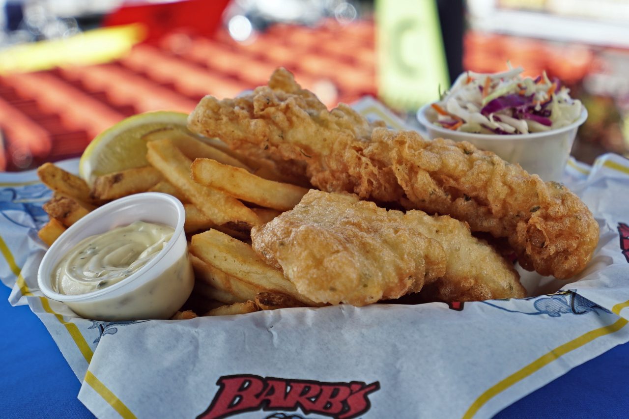 A basket of fish and chips with a side of coleslaw and tartar sauce