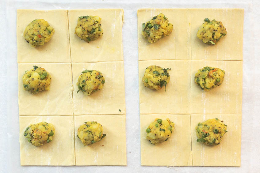 Puff pastry topped with samosa mixture on a sheet tray