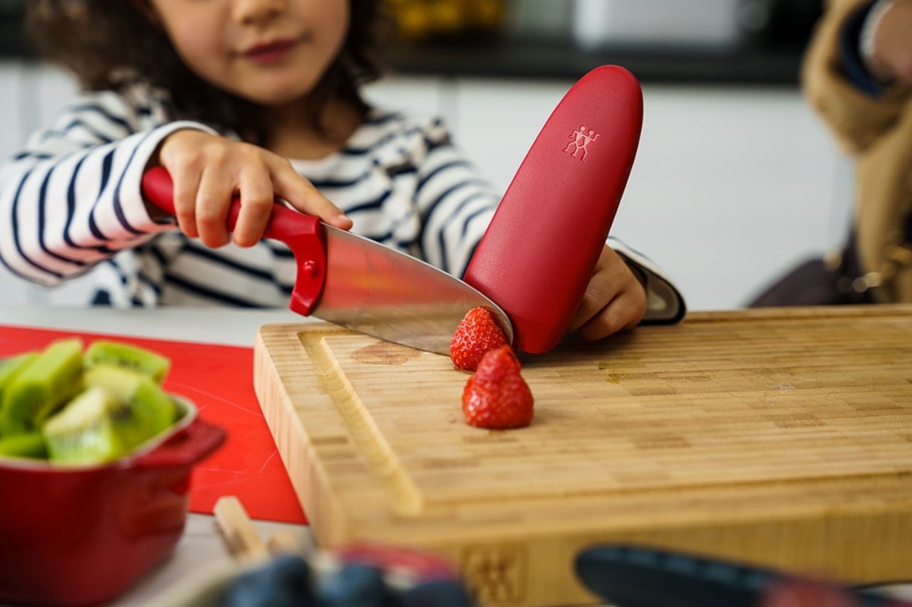 Little girl cutting fruits with a knife