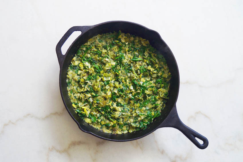 Leeks, spinach and parsley in a cast iron pan for creamy shakshuka