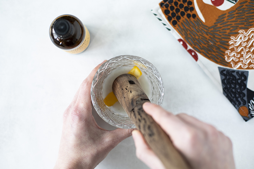 Muddling ingredients for a butter pecan old fashioned