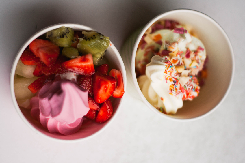 Two cups of frozen yogurt with assorted toppings