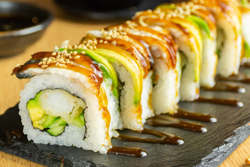 Close-up shot of a dynamite sushi roll topped with torched fish