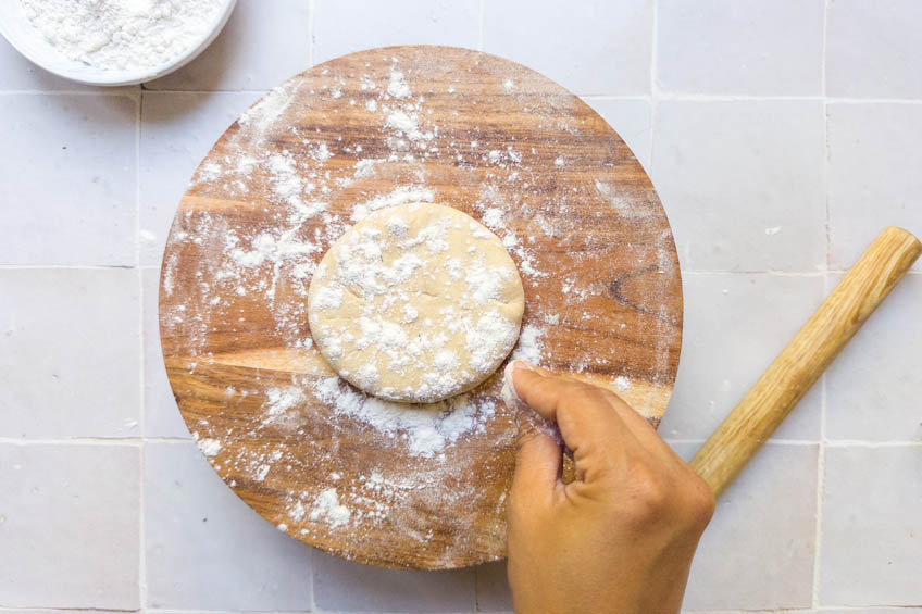 Aloo paratha dough ball being dusted with flour