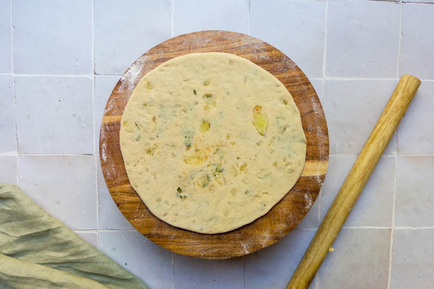 A rolled out aloo paratha on a cutting board