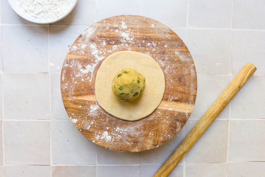 A ball of potato filling on top of paratha dough