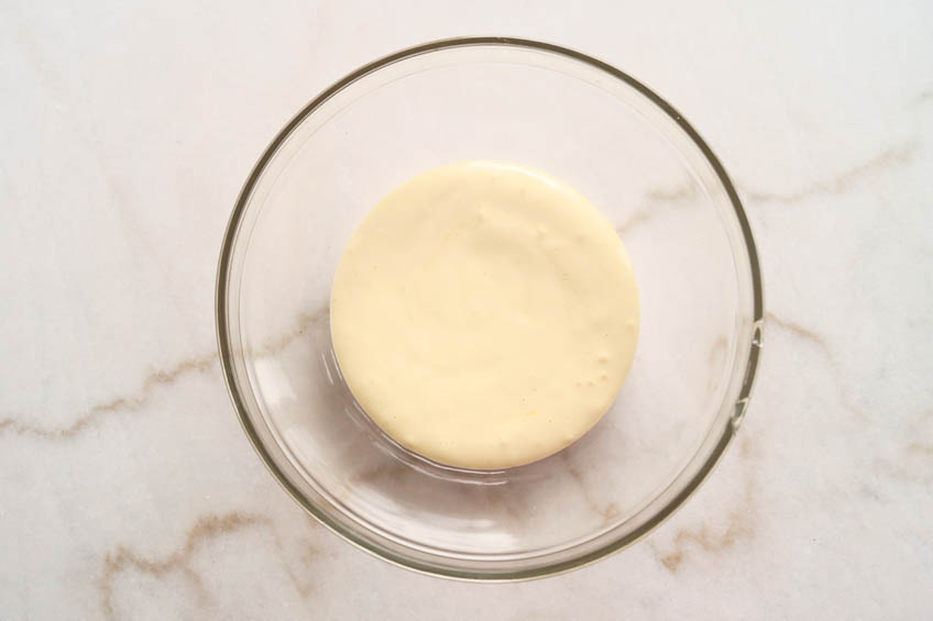 Whisked egg yolks and powdered sugar in a mixing bowl.