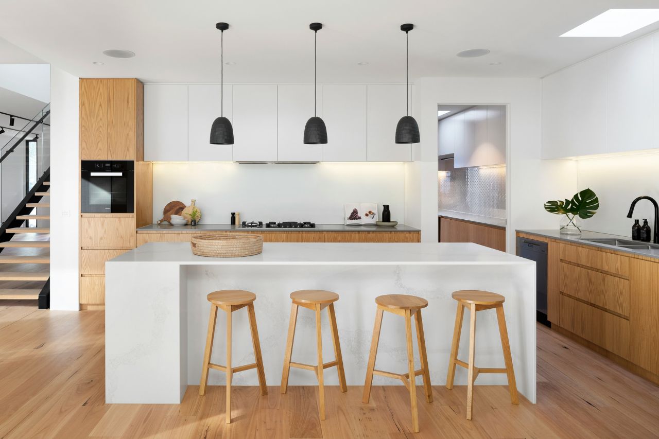 Bright white kitchen with black lights and four wooden stools