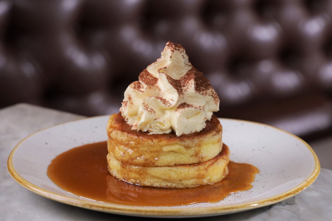 Fluffy tiramisu pancakes with whipped cream, chocolate powder and syrup