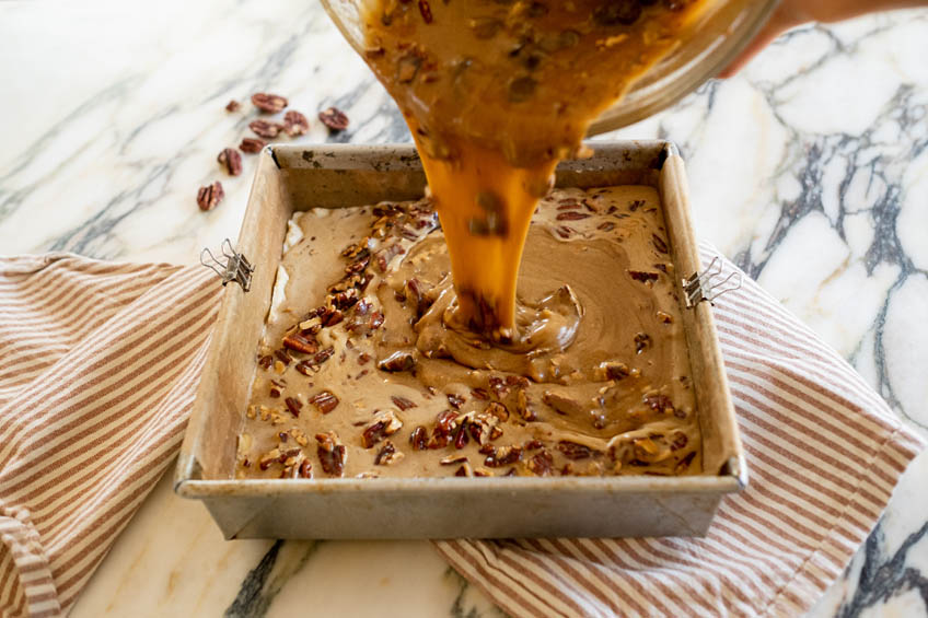 Brown butter maple pecan filling being poured over shortbread base.