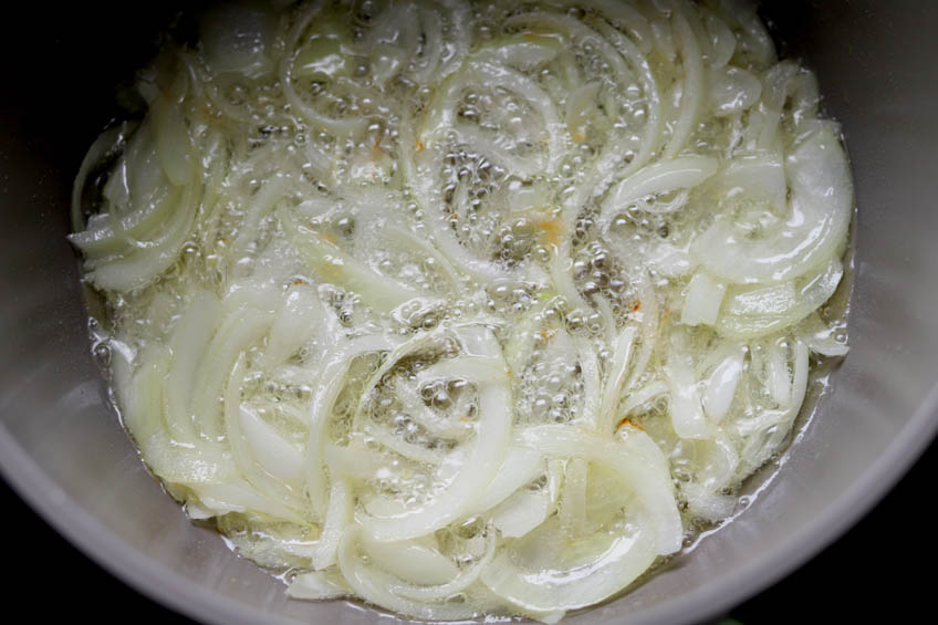 Onions being sauted in oil in a Dutch oven