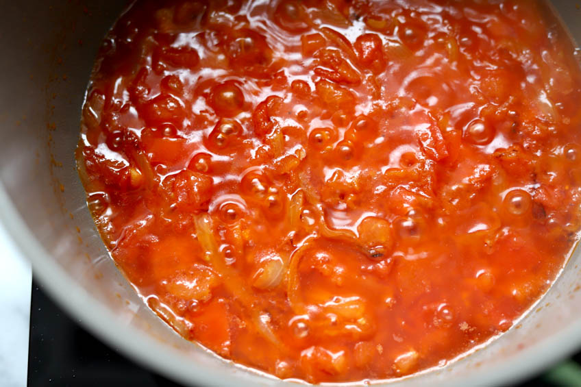 Seasoned tomatoes and onions simmering in a Dutch oven