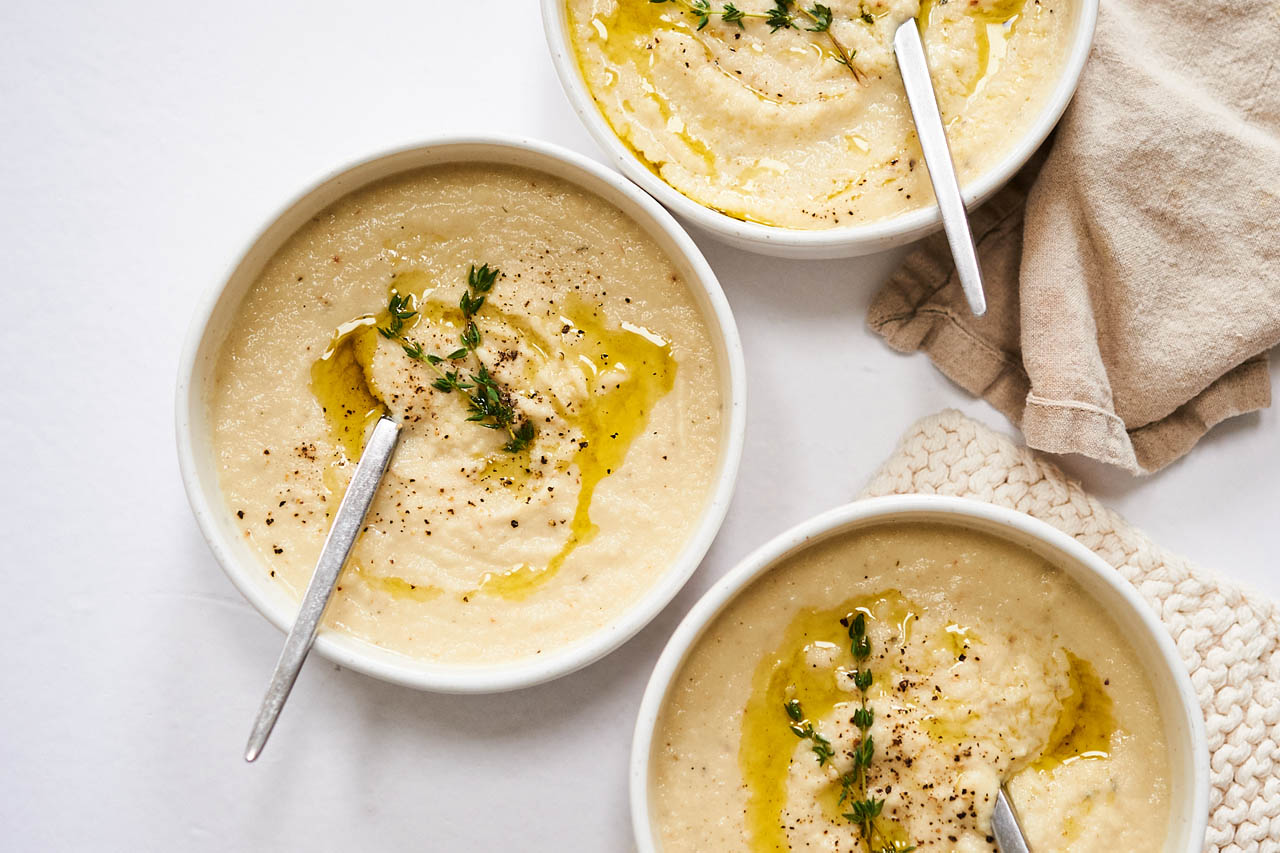 Roasted garlic and cauliflower soup in three bowls.