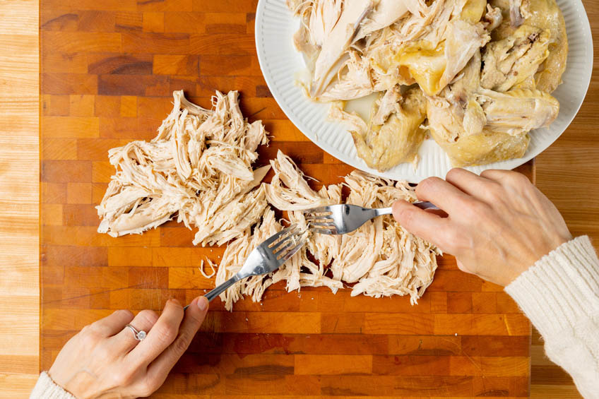 Chicken being pulled apart on a cutting board