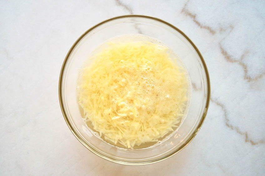 Grated potatoes in a bowl of cold water