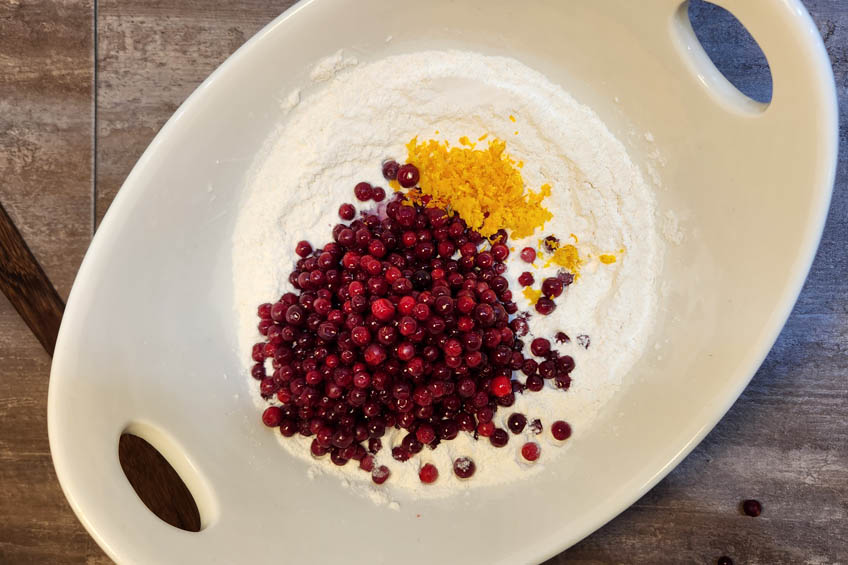 Orange zest and cranberries in a bowl with dry ingredients for arctic cranberry orange muffins