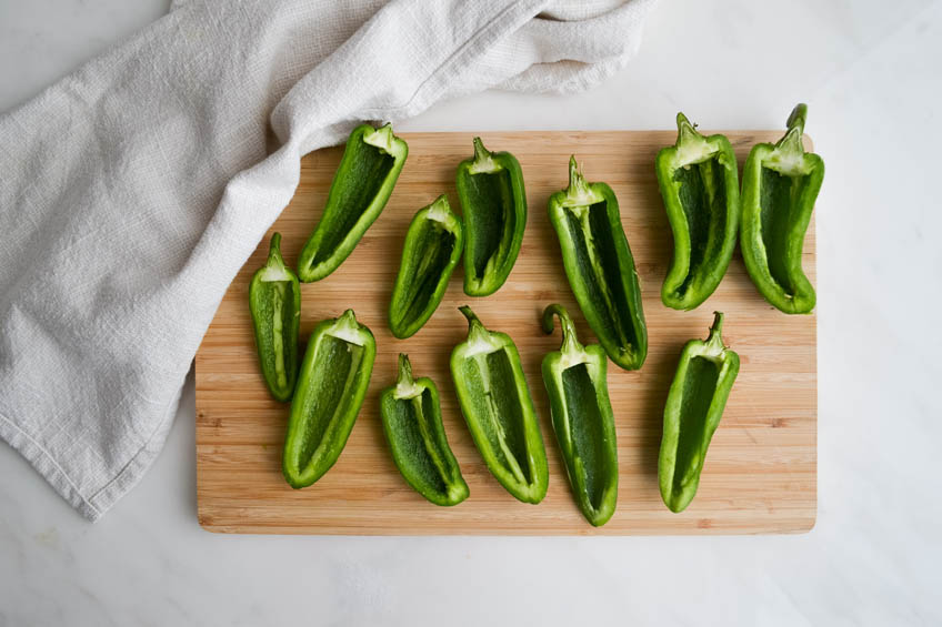 Jalapenos cut in half on a cutting board