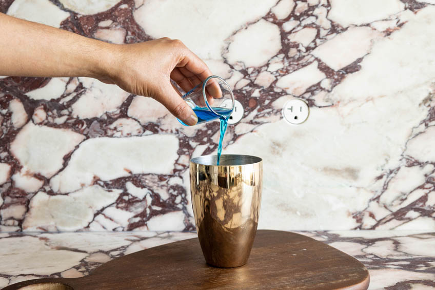 Blue curacao being poured into a cocktail shaker