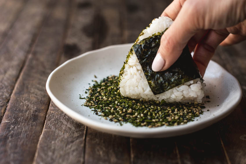 Onigiri being rolled in furikake