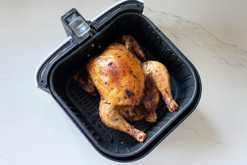 A roasted chicken in an air fryer basket