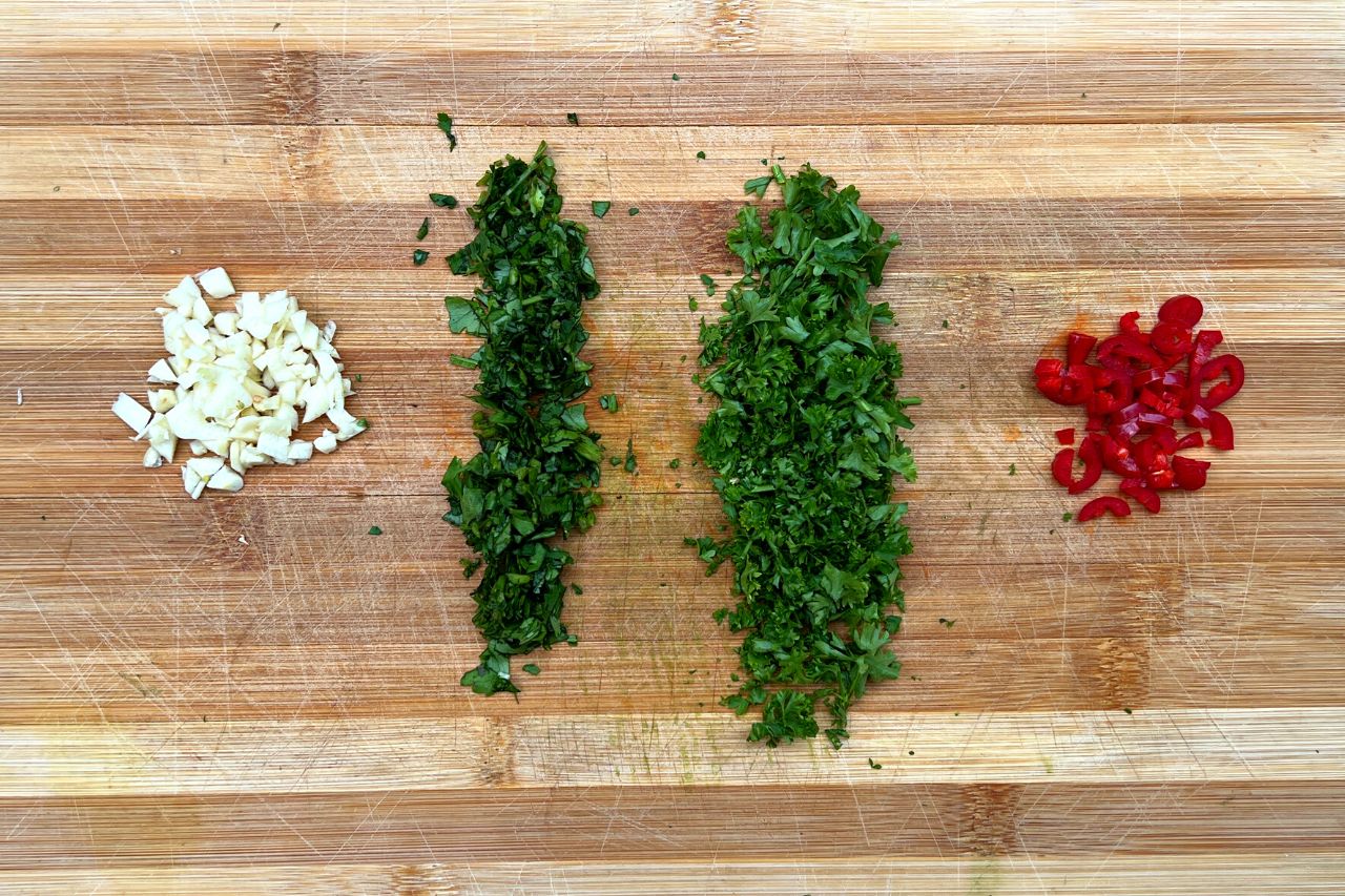 cilantro, pepper, garlic and parsley chopped on a cutting board