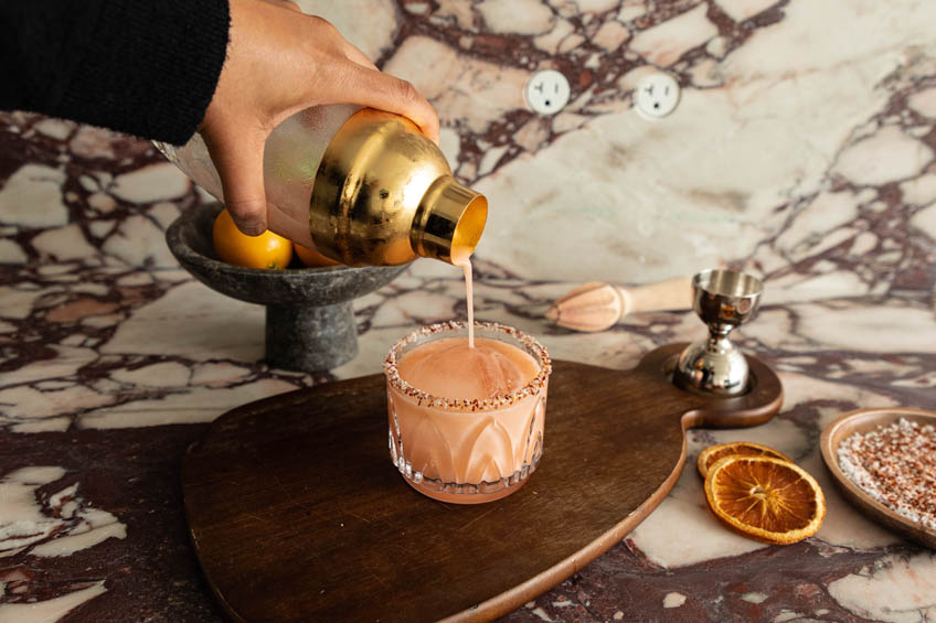 Aperol margarita being strained into a glass