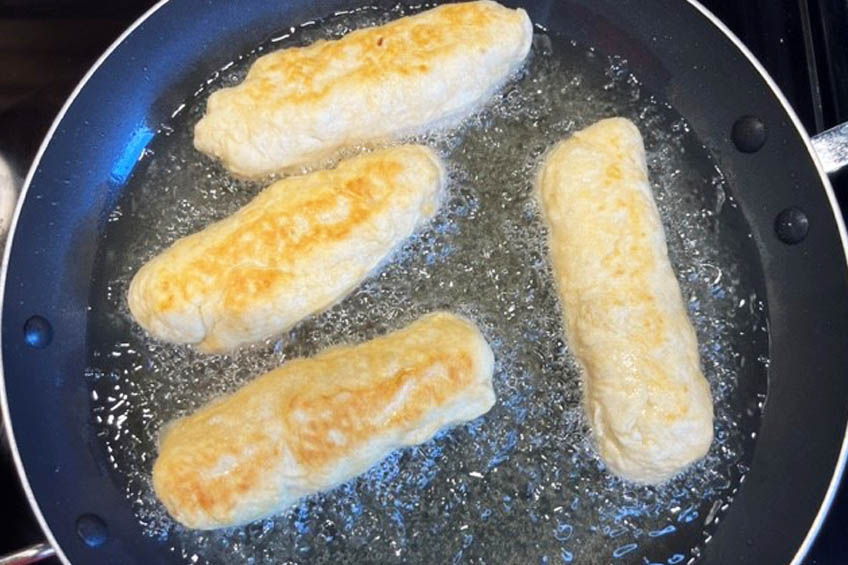 Bannock dogs frying in a skillet