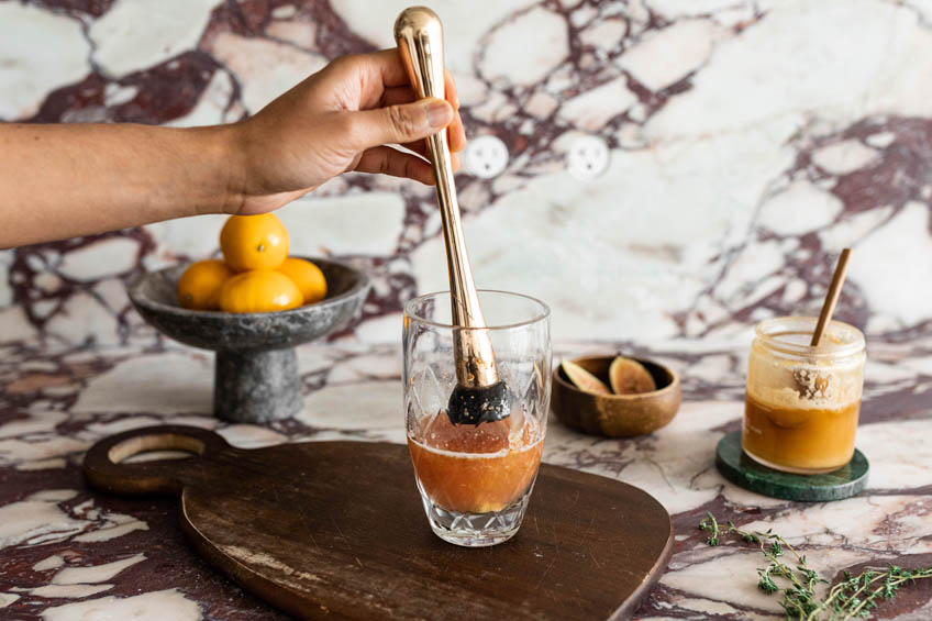 Figs being muddled in a cocktail shaker