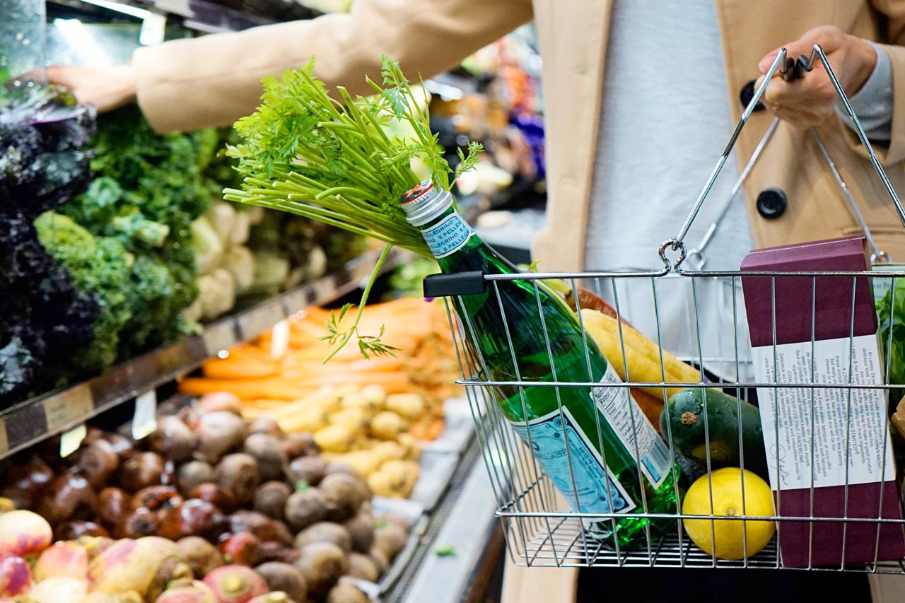 A woman adding produce to her cart in a grocery store