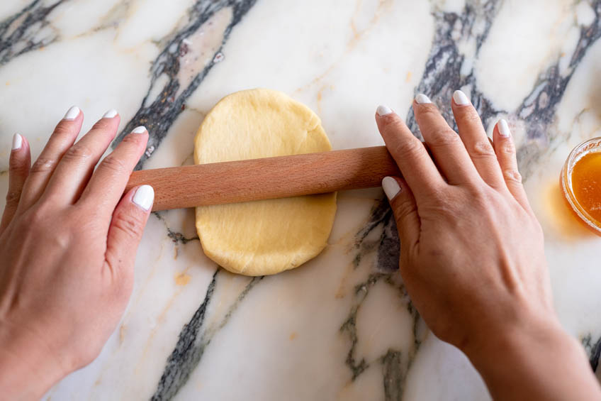 A small piece of dough being rolled out for Chinese hotdog flower buns