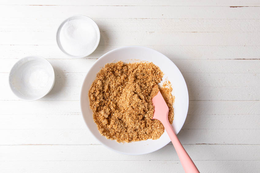 Graham cracker crumbs being mixed with melted butter in a bowl