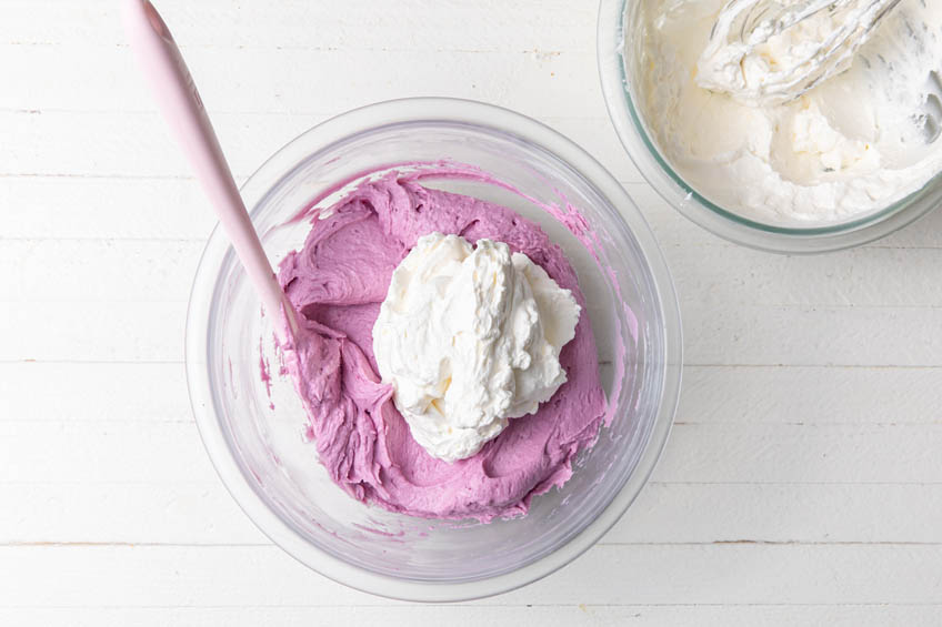 Whipped cream being combined with ube cheesecake filling