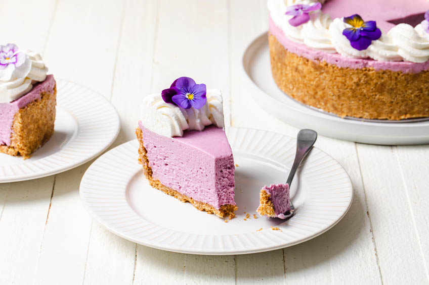 A slice of ube cheesecake with a bite taken out