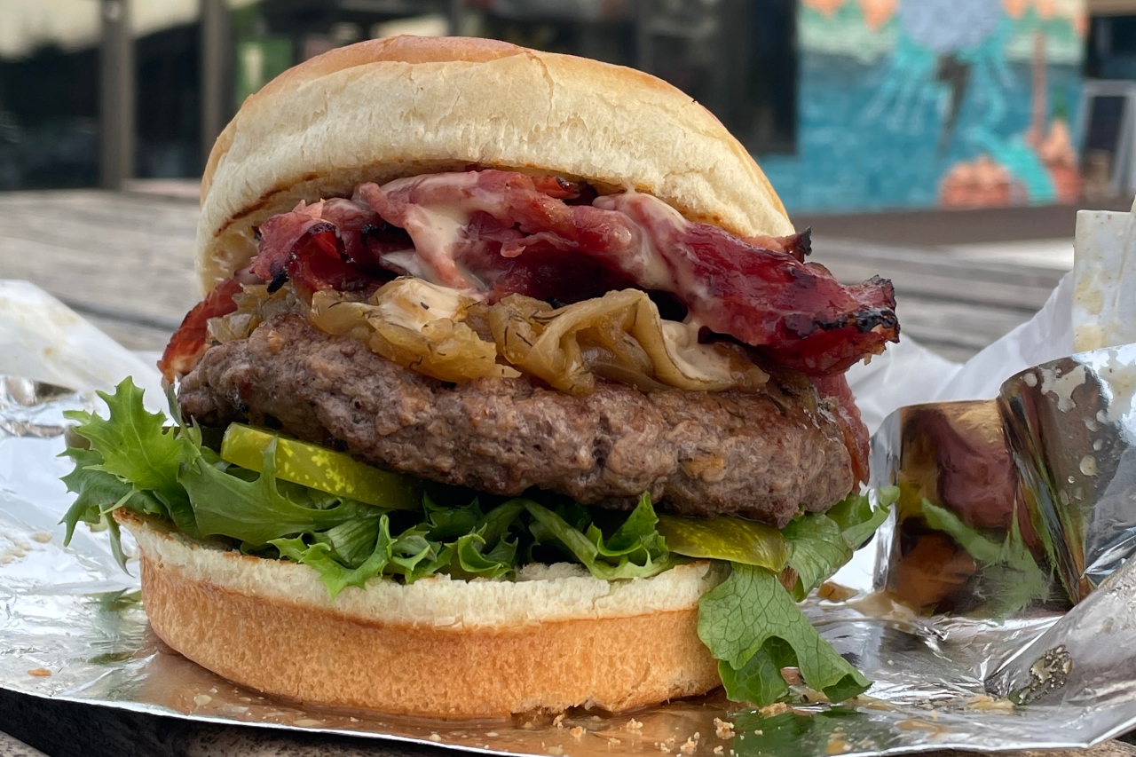 A beef burger topped with peameal bacon, caramelized onions, sautéed mushrooms, aged white Cheddar cheese, BBQ sauce, lettuce and tomato.