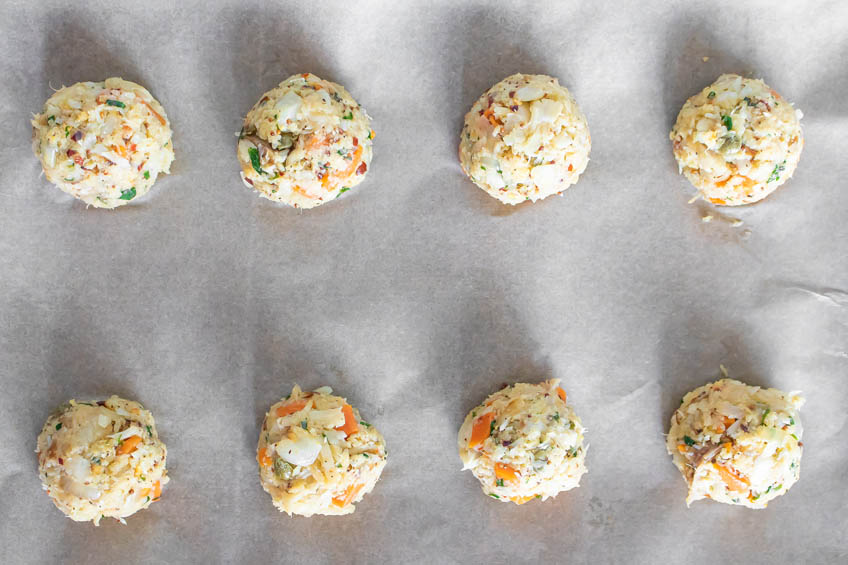 Uncooked cod fish cakes on a parchment-lined baking sheet