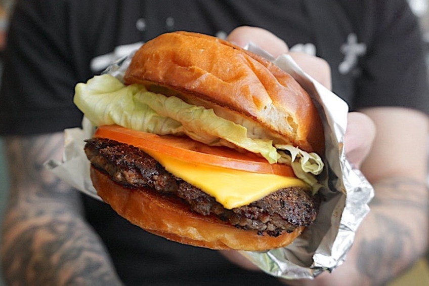 A beef burger topped with crispy maple ham, Cheddar cheese, lettuce, tomato, pickle and signature sauce on a toasted potato bun.